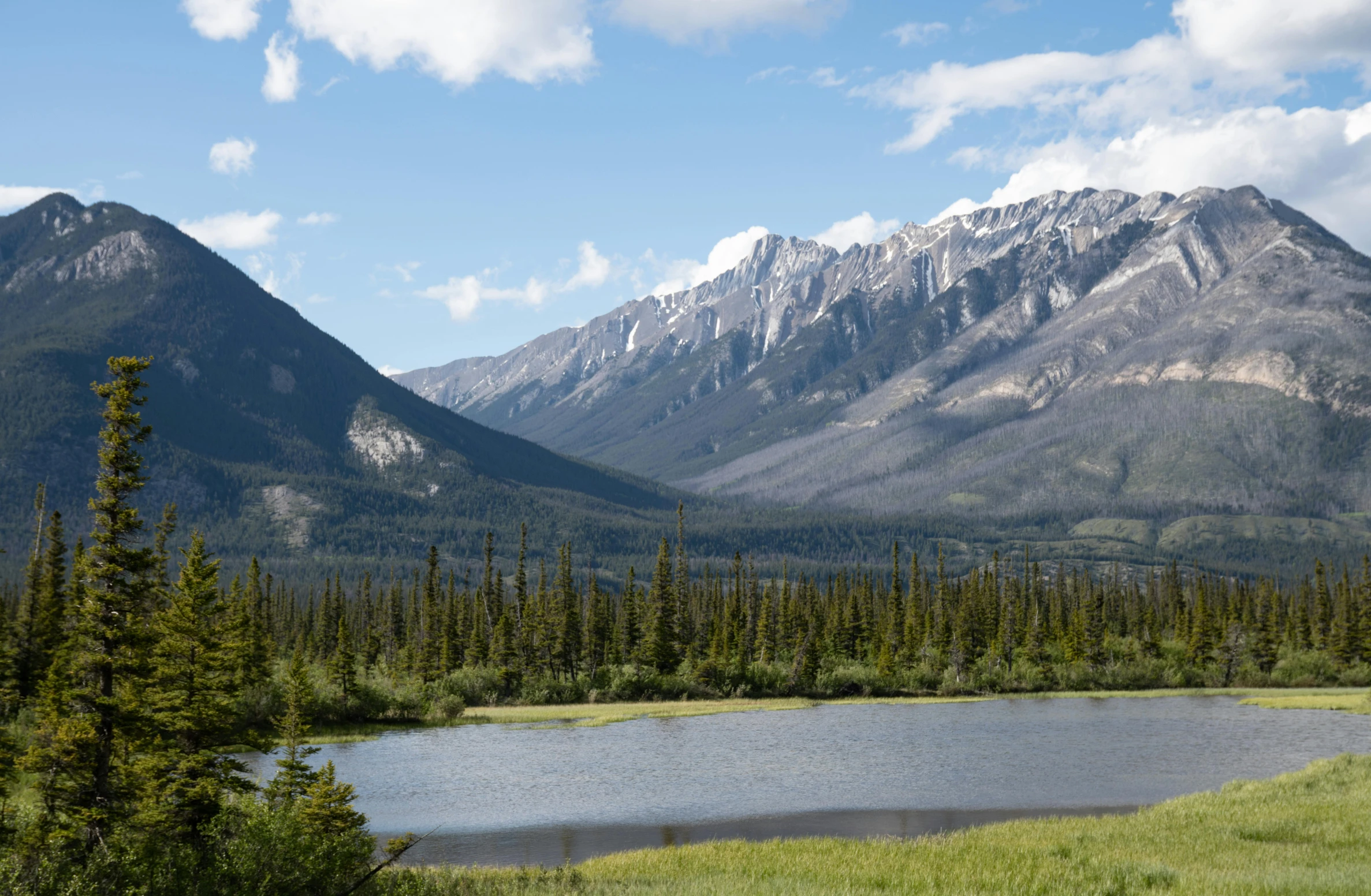 a po taken from the valley floor, of a mountain range with a lake below it