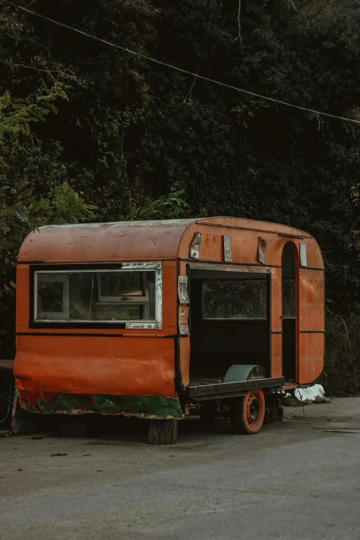 an orange old style camper sitting on the road