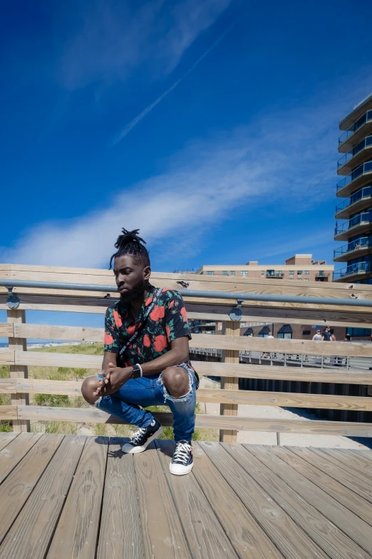 a black man squatting on the deck of a building