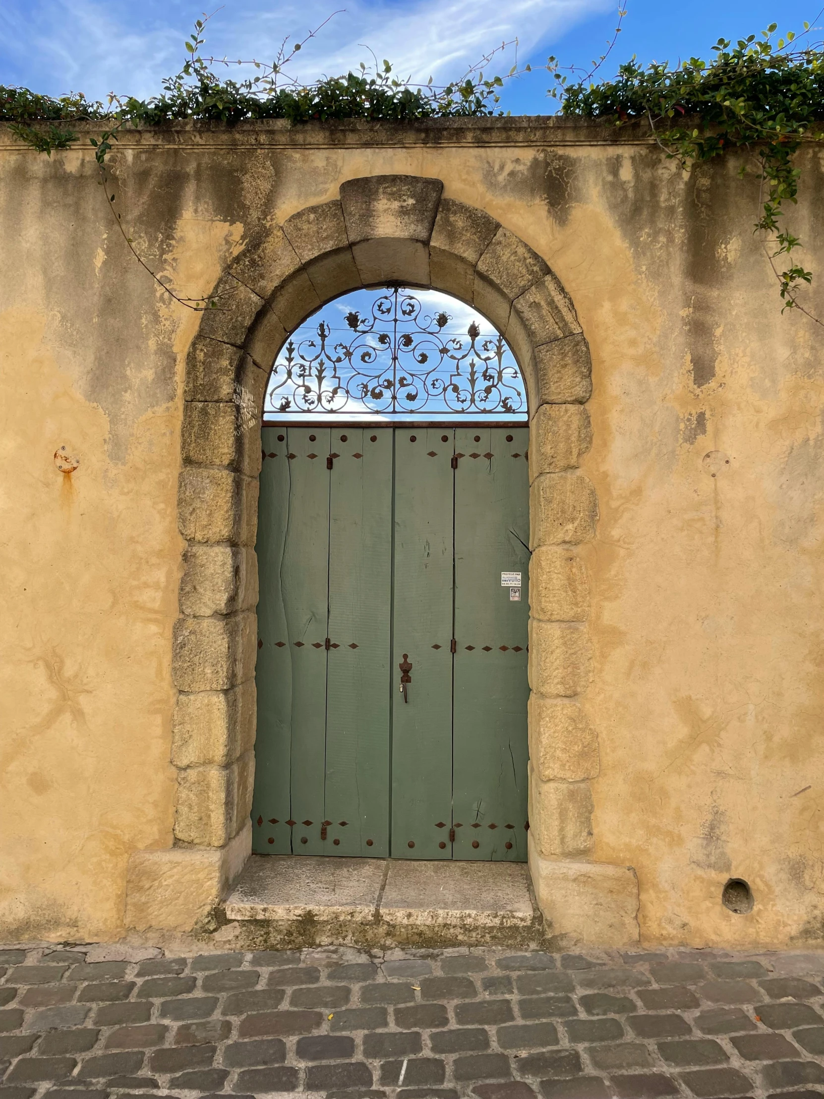 a large doorway on a stucco wall with an arched window and light green doors