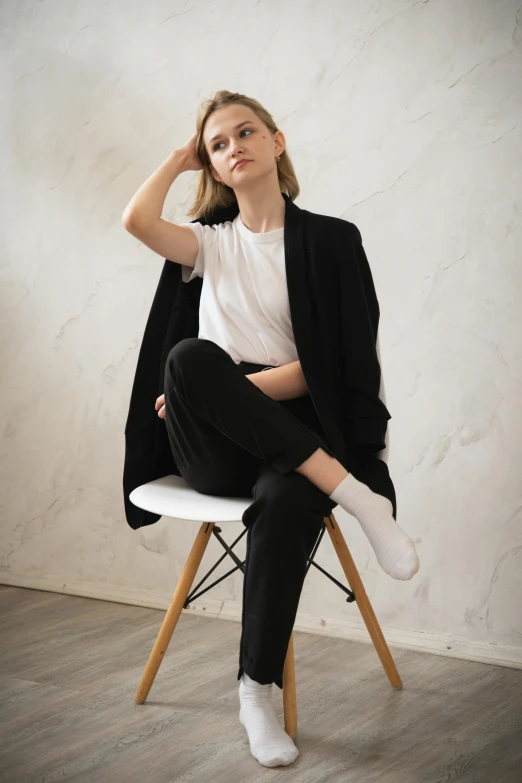 a woman in white shirt and black blazer sitting on wooden chair