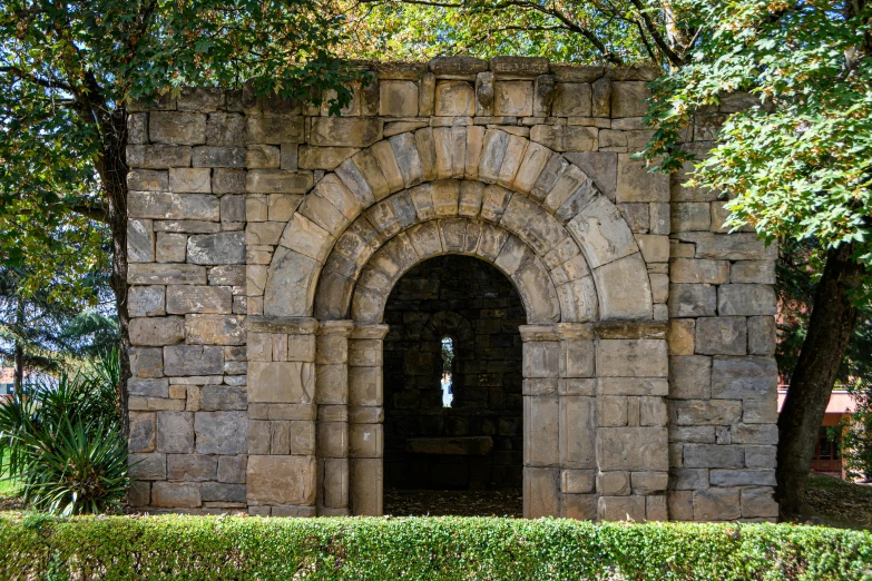 stone building with arched doorway in park setting