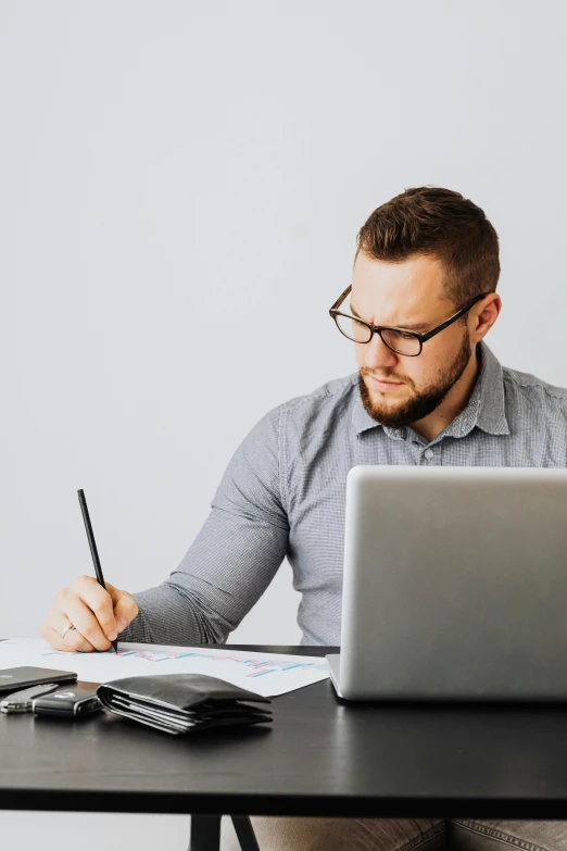 a man with glasses sitting at a desk with a laptop