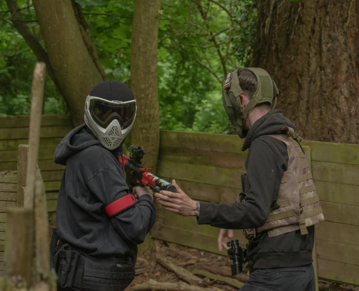 two men talking to each other with paintball masks on