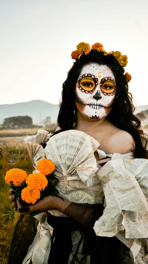 a girl wearing sugar skulls and floral adorned makeup with an orange bouquet