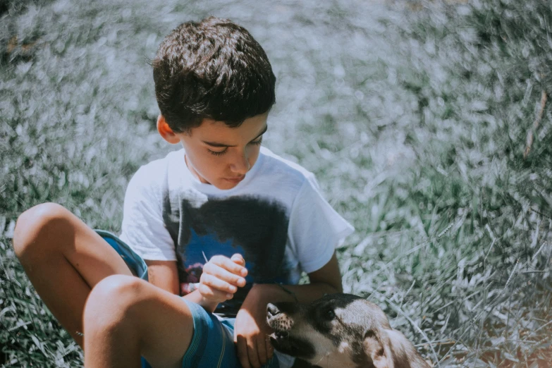 a boy sits in the grass with his puppy