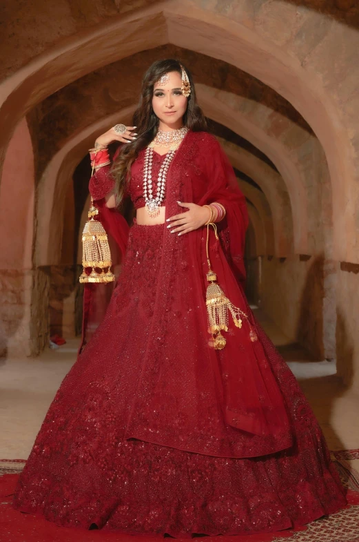 a woman in a red suit and a hat poses