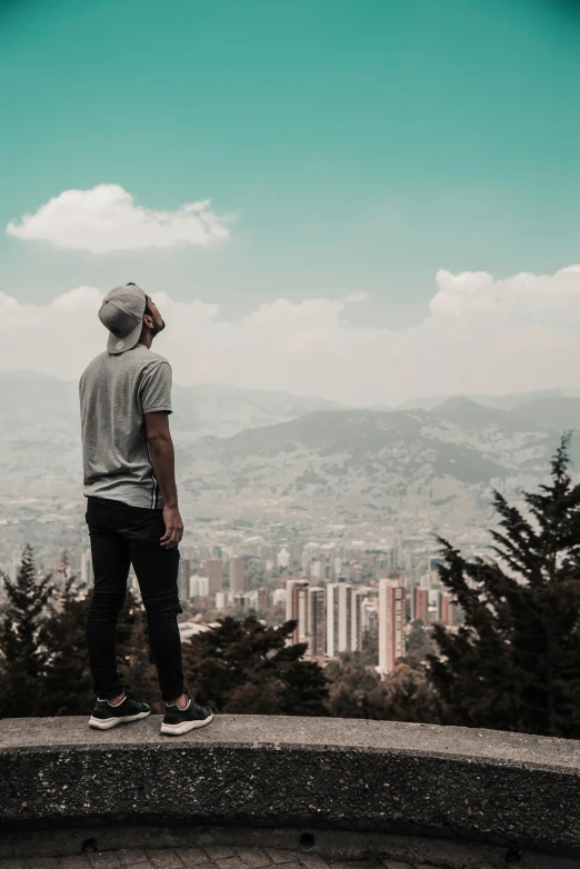 man looking down at large city with green trees in the background