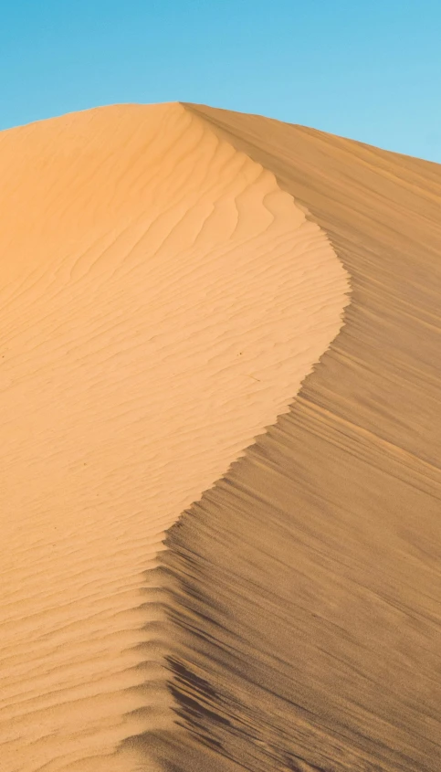 an airplane flying over the top of a desert sand dune