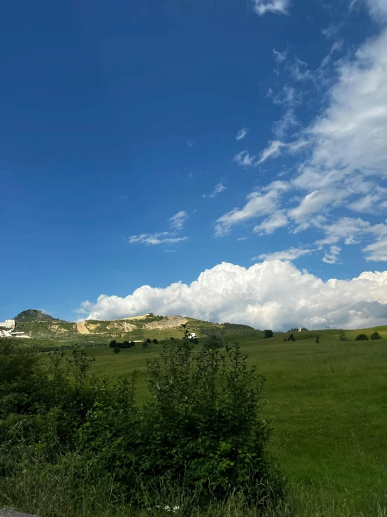 clouds, blue sky and green hills are in the distance