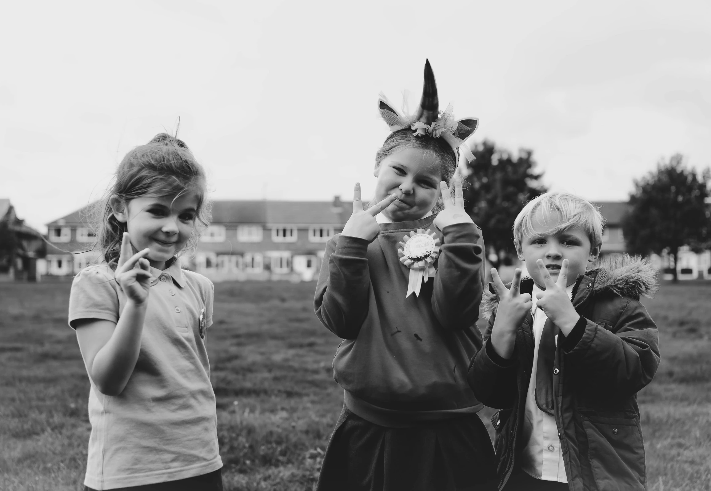 three girls standing in the grass wearing unicorn costume