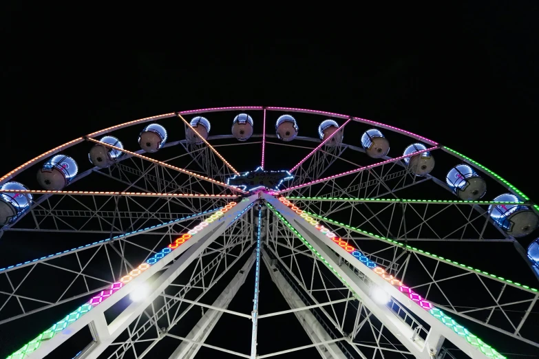 a ferris wheel with multicolored lights lit up at night