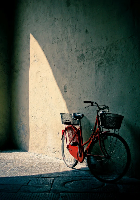 red bicycle with basket leaning up against a wall