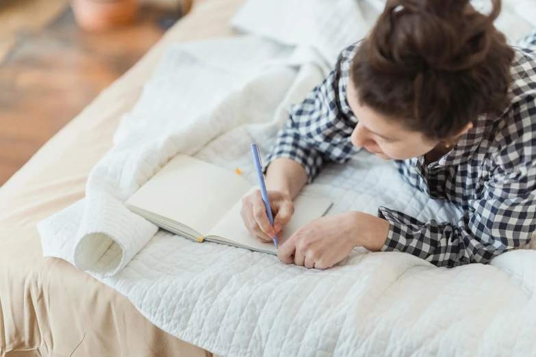 a woman sitting on a bed and writing