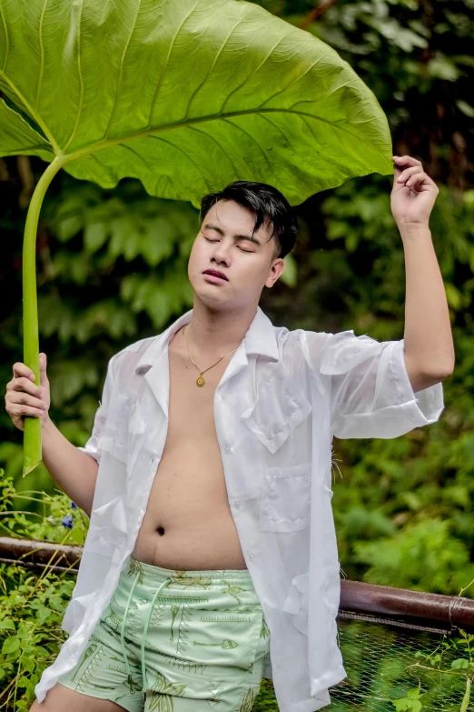 a shirtless man holds up an umbrella above his head