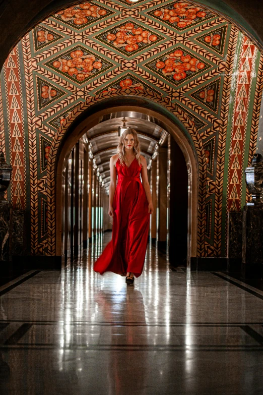 a woman in red dress walking down a building