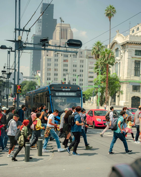 many people crossing the street near a bus