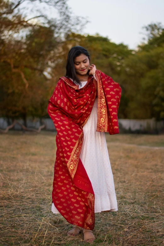 a young woman in a long red dress is talking on her cellphone