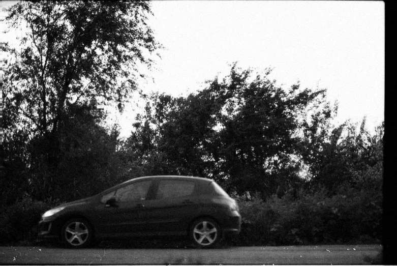 a parked car sitting next to a tree in a wooded area