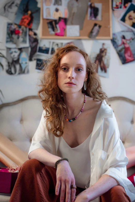 a woman sitting in a bed near a bunch of pictures on a wall