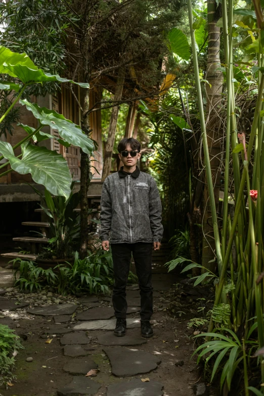 man in sunglasses standing by some green plants