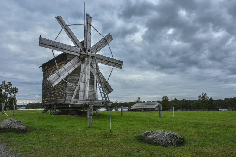 a windmill standing in a field, some very tall grass and one sign next to it