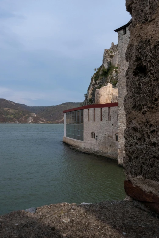 a building is sitting in the water near some large rocks