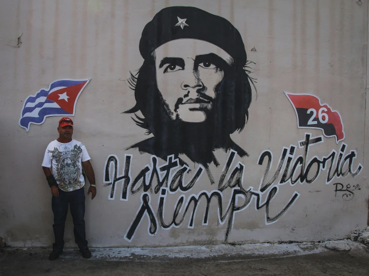 man standing next to mural with cheesy writing on wall