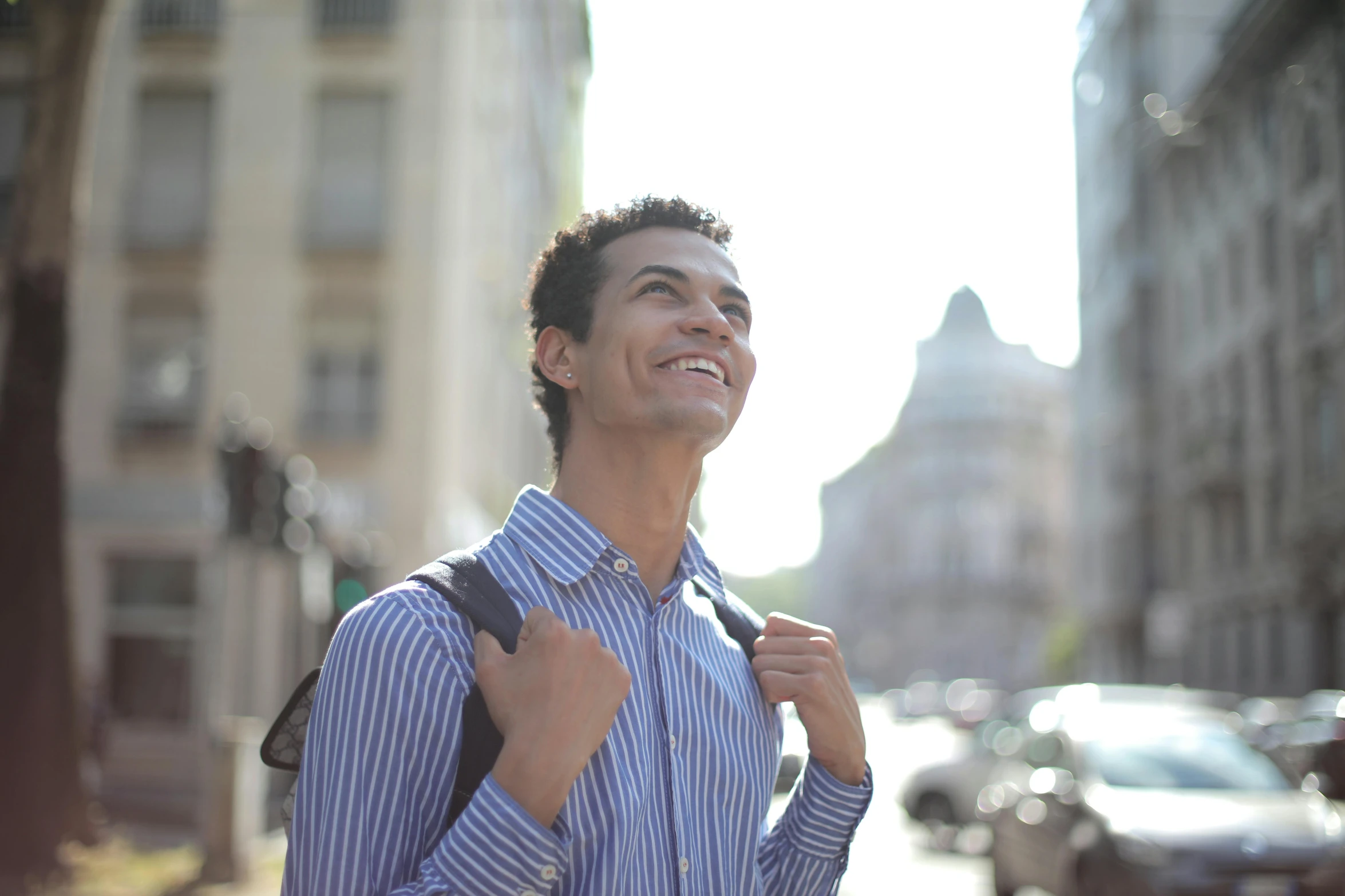 a young man smiles as he poses with his backpack