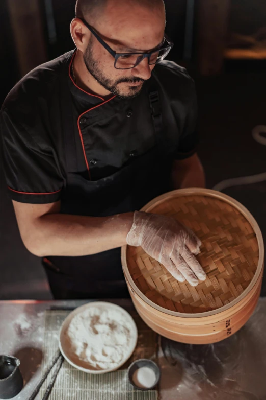 a man in a kitchen adding flour on top of a wooden pan