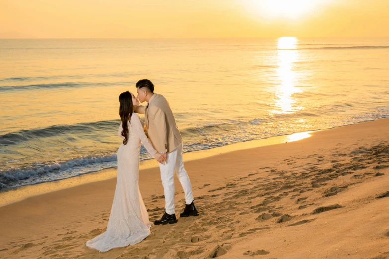 a man and a woman pose for the camera on a beach at sunset