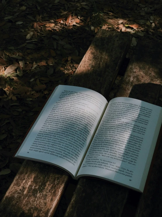 an open book on a wooden bench outdoors