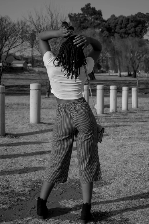 black and white po of woman standing with a purse on her back