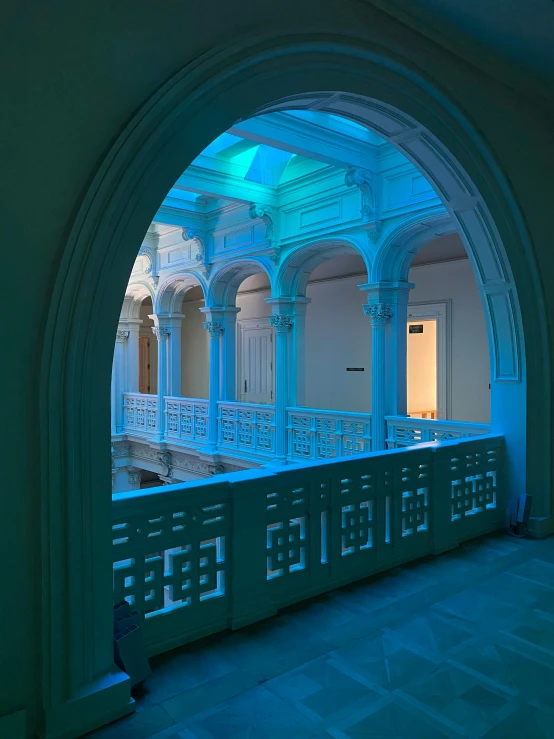 a lit hallway with archways and tiled floor