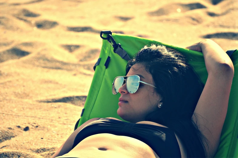 a girl lays in a lounge chair on the beach