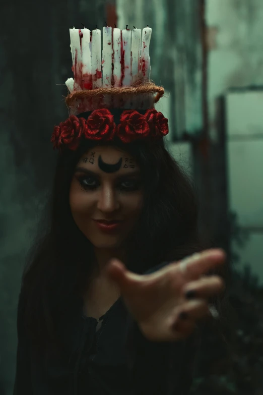 a woman with dark hair and makeup is posing wearing a red candles and flowers crown