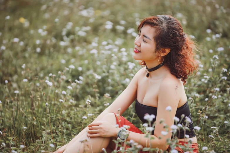 a woman with long hair sitting in the grass