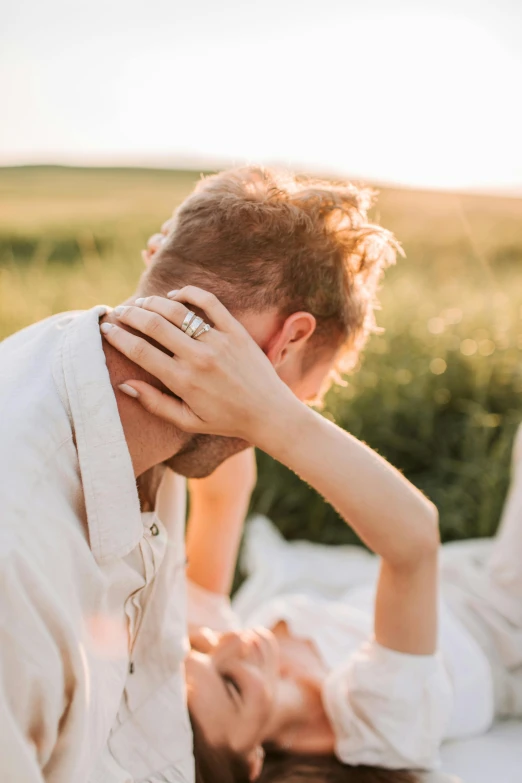 a couple laying on their backs in a field looking at the camera