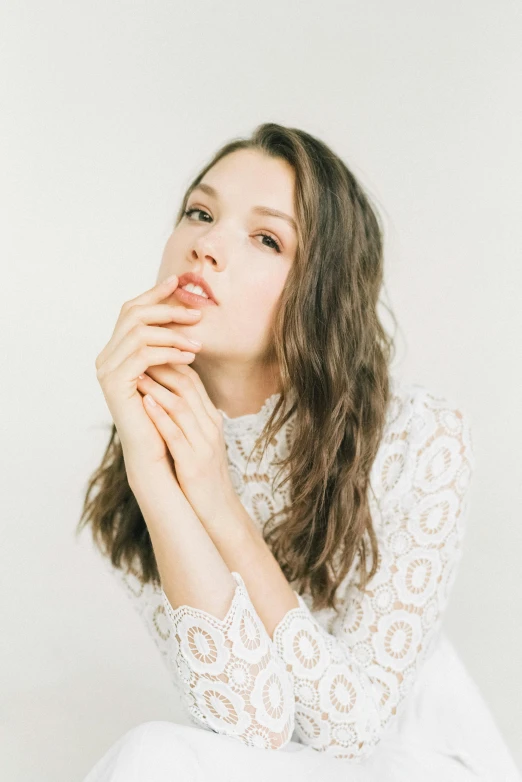 young woman in white dress looking upward with arms folded