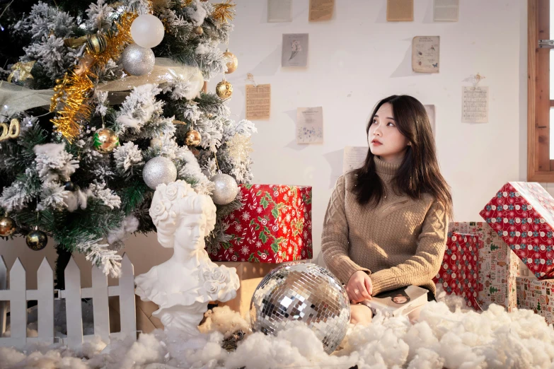 a woman that is sitting on a floor in front of a christmas tree