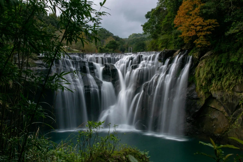 a large waterfall cascades into a lake surrounded by green vegetation