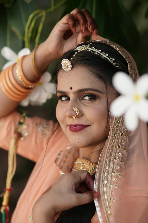 a woman in a traditional saree has a flower pinned to her forehead