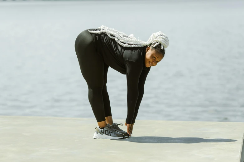 woman in black pants with her head down leaning forward