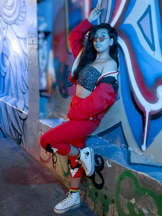 a woman posing on the wall of a graffiti filled alley