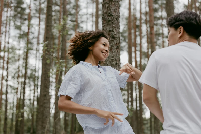 young woman dancing outside in the woods with her male companion