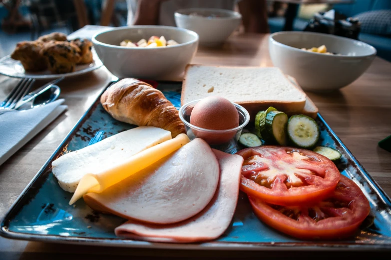 a blue tray with bread, tomatoes, meat and vegetables