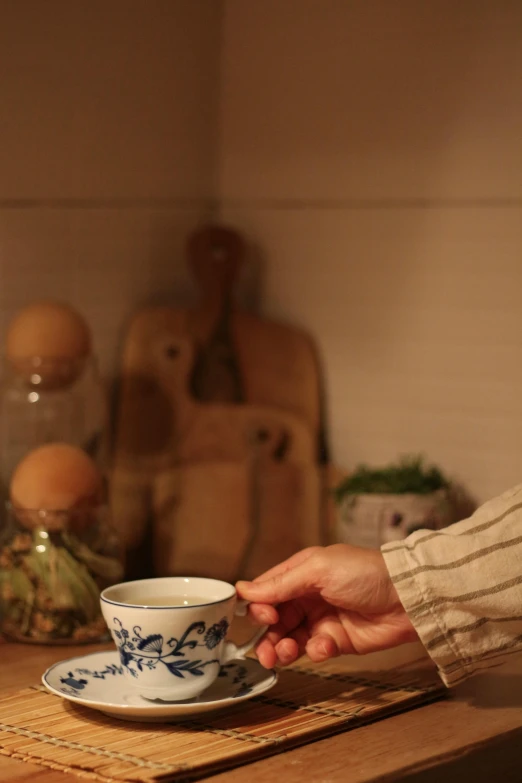 a person is reaching out to a teacup