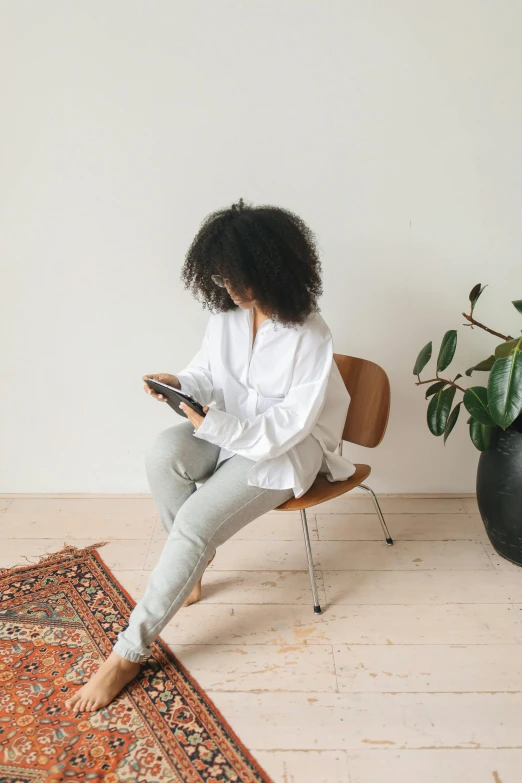 a woman with curly hair sitting on a chair using her phone