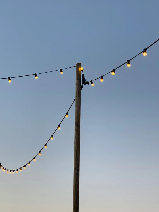 string lights hang down on electric poles with clear skies in the background