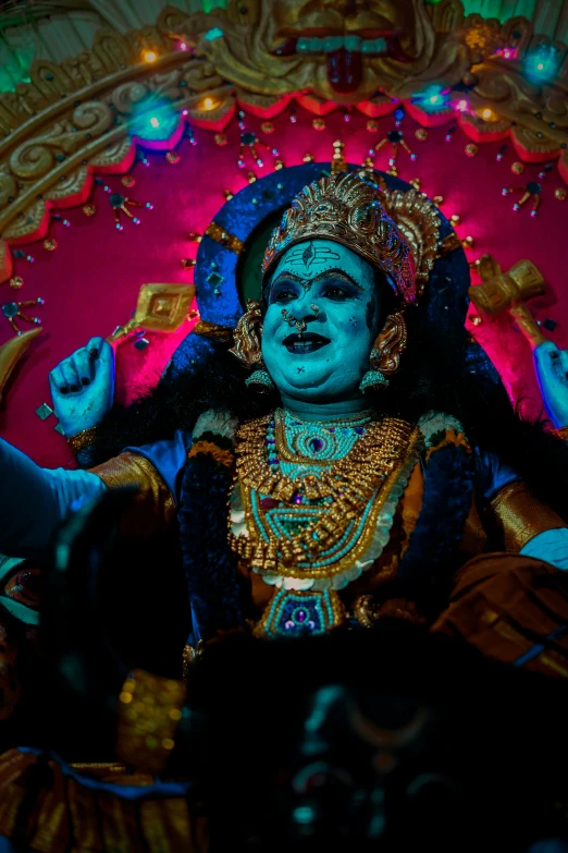 a idol dressed in blue and golden sits in the center of the stage